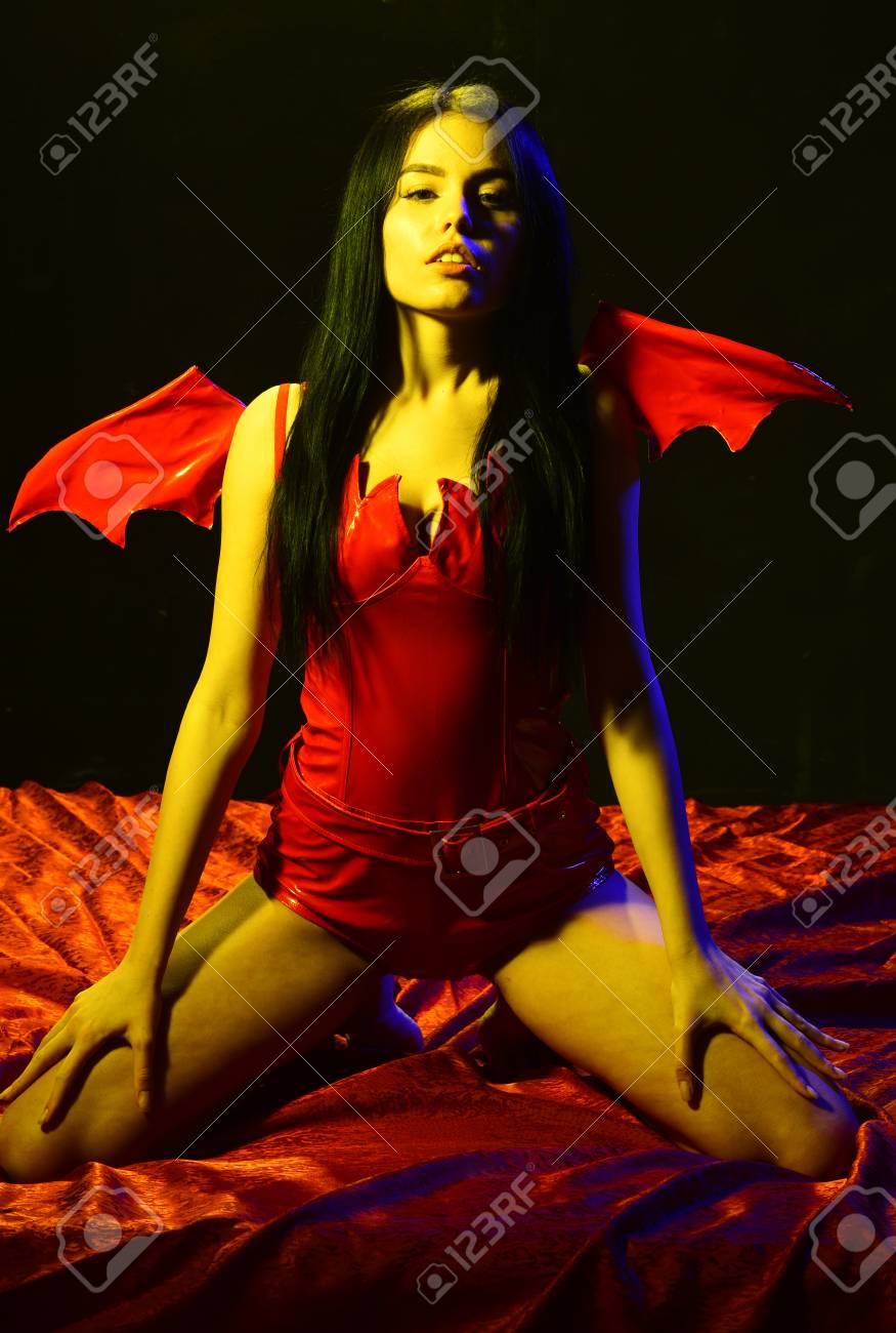Girl Sexy Demon With Wings, Devil Full Of Desire. Lady Sexi Dressed As  Demon, Devil, Black Background. Sexy Devil Concept. Demon Sexy Girl Sit On  Silk Sheets. Woman On Passionate Face Play
