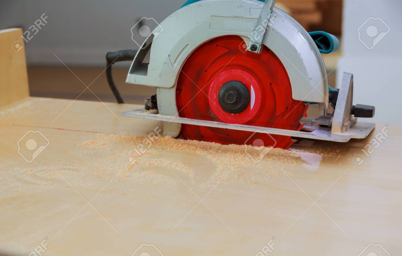 Carpenter Cutting A Kitchen Cabinet With The Disk Saw During