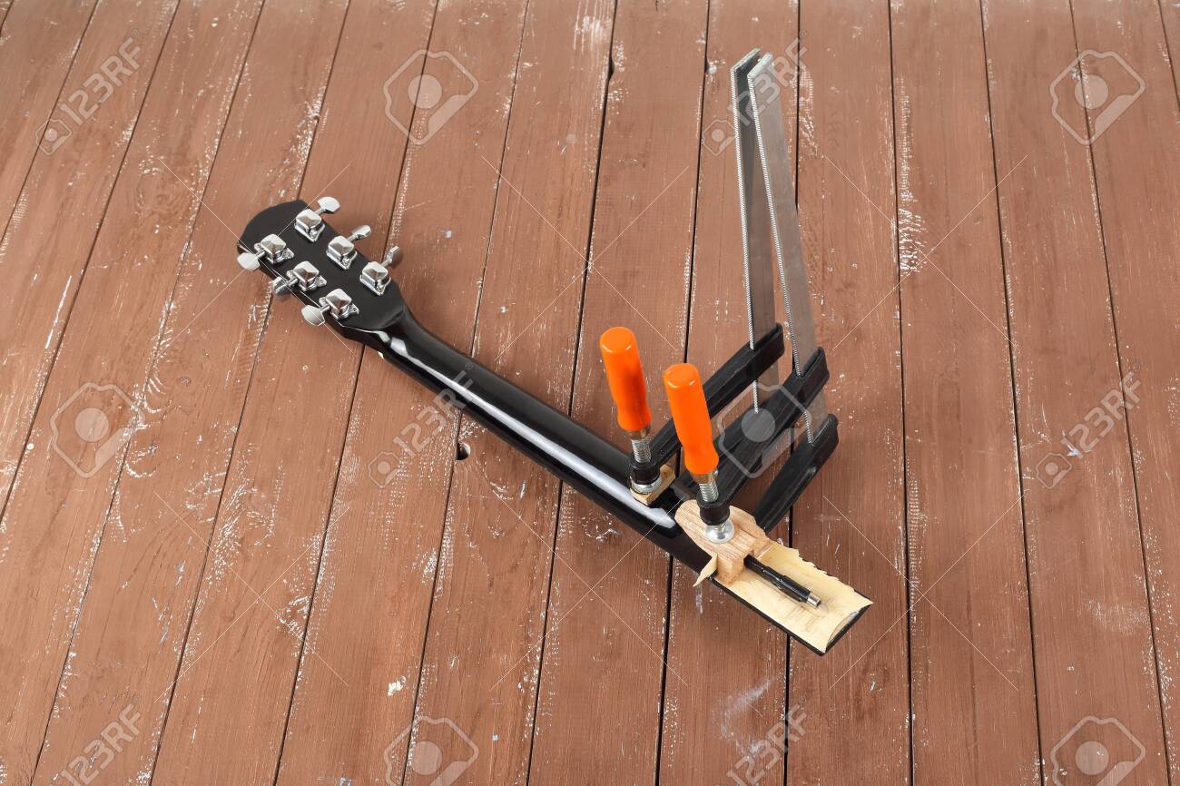 Guitar repair and service - Clamping a guitar neck wooden background - 121652846 Guitar repair and service - Clamping a guitar neck wooden background - 121652846