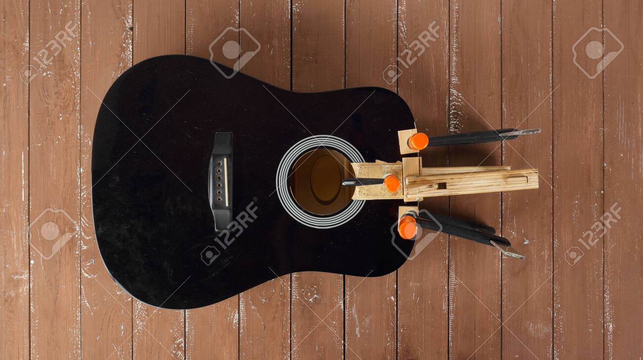Guitar repair and service - Repair clamping broken sound board acoustic guitar top view wooden background - 128715141 Guitar repair and service - Repair clamping broken sound board acoustic guitar top view wooden background - 128715141