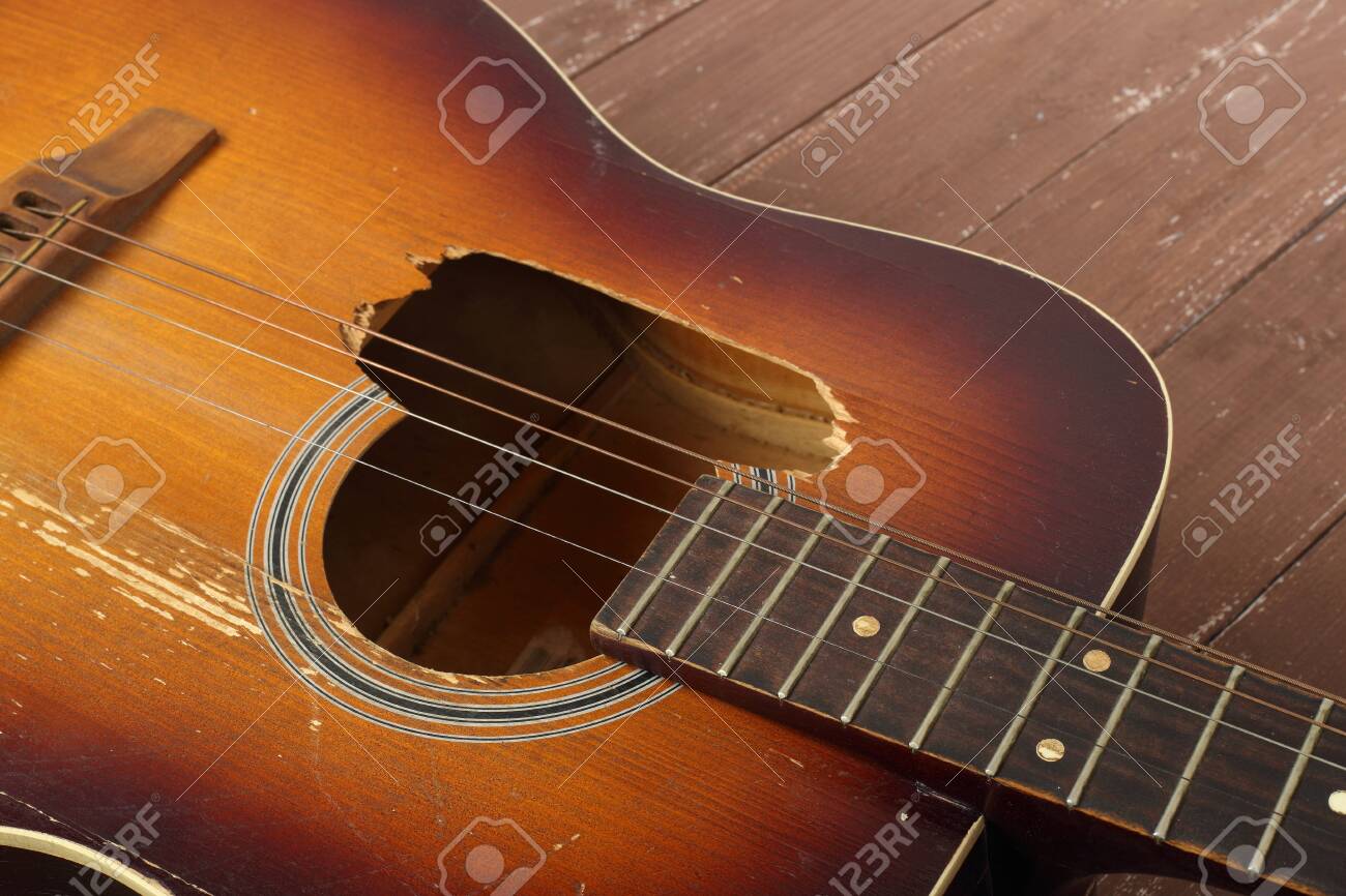 Musical instrument - Closeup fragment broken classic acoustic guitar on a wooden background. - 144839391 Musical instrument - Closeup fragment broken classic acoustic guitar on a wooden background. - 144839391