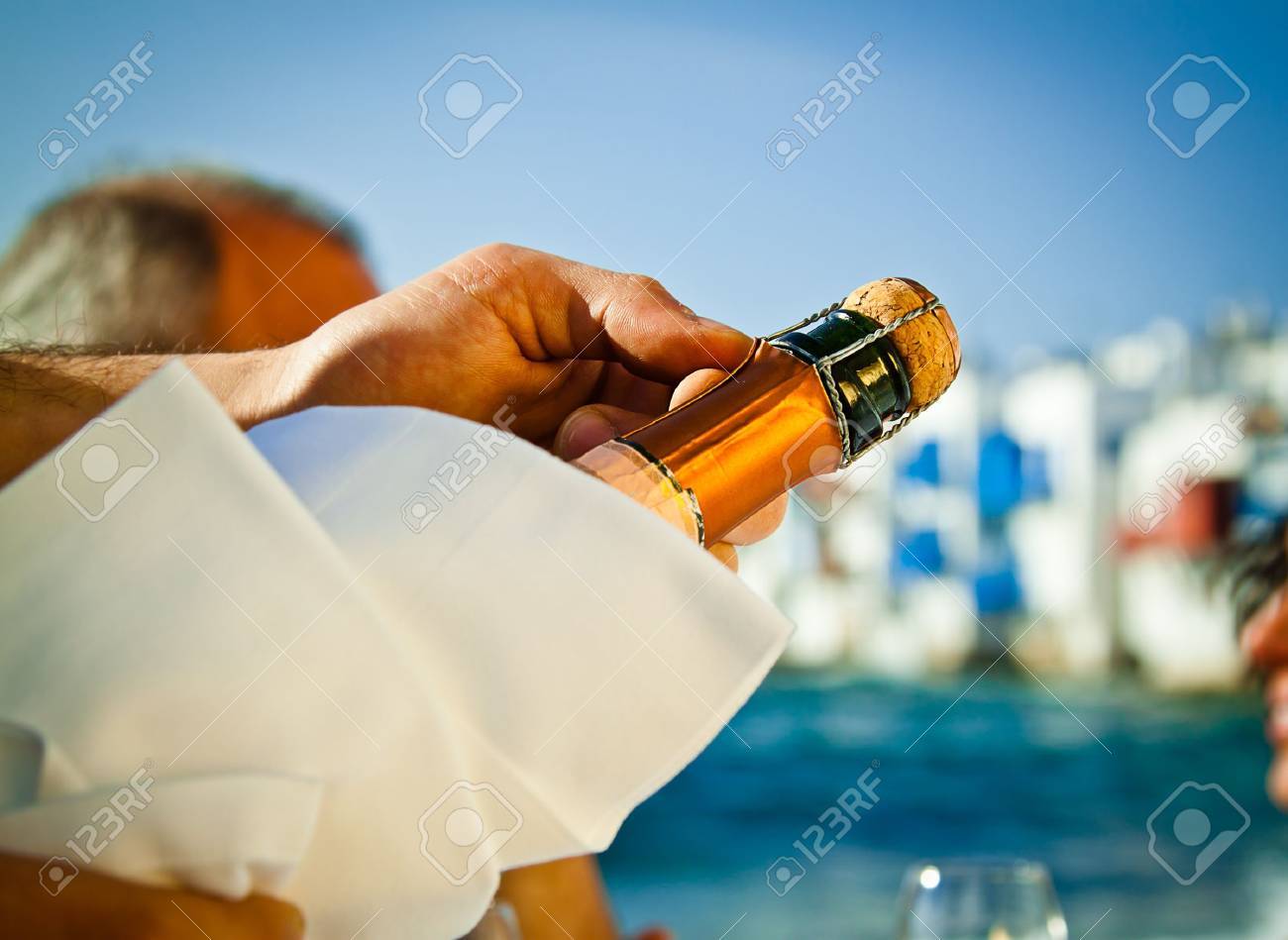 Popping a bottle of champagne open by the sea - 13896755 Popping a bottle of champagne open by the sea - 13896755