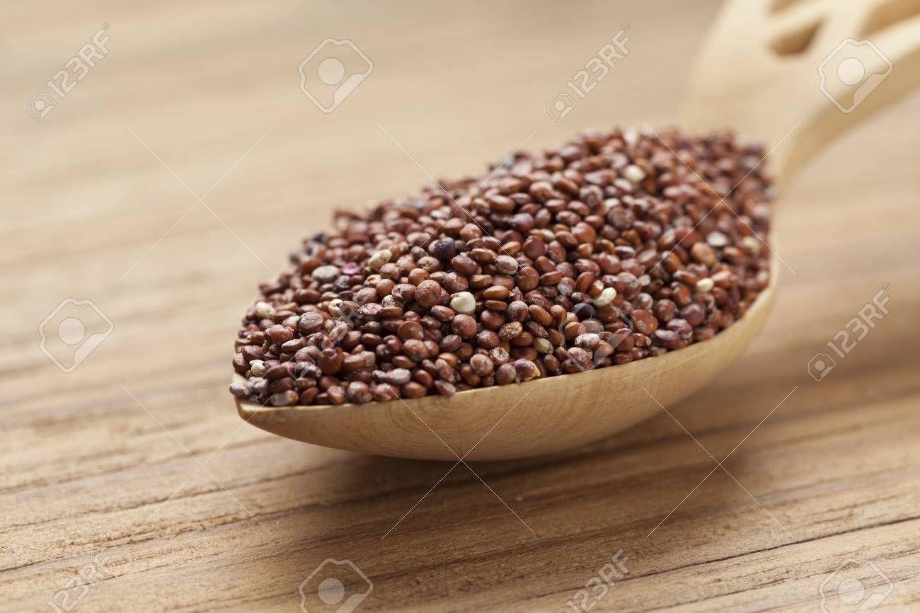 Red raw Quinoa seeds on a wooden spoon - 44875497 Red raw Quinoa seeds on a wooden spoon - 44875497