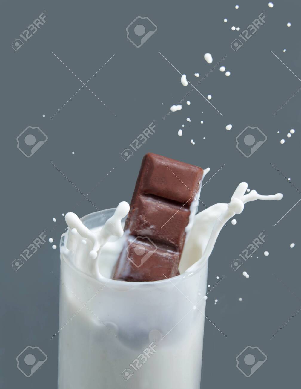 Milk Splash From A Chocolate Bar Drop Into A Glass Of Milk, On The Gray  Background. Stock Photo, Picture and Royalty Free Image. Image 139412179., image size:1008x1300