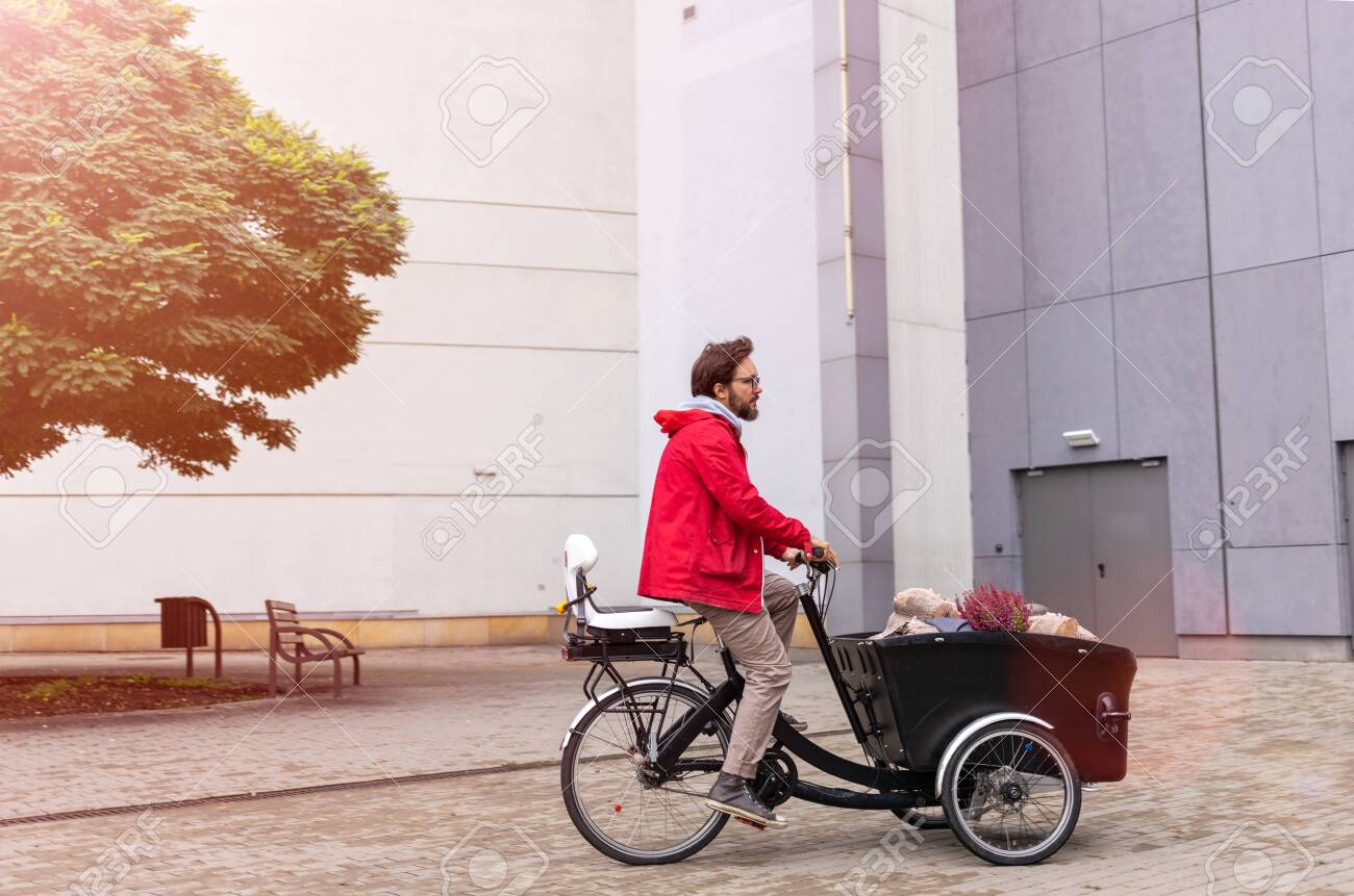 Young man going back from shopping with a cargo bike - 130738851 Young man going back from shopping with a cargo bike - 130738851