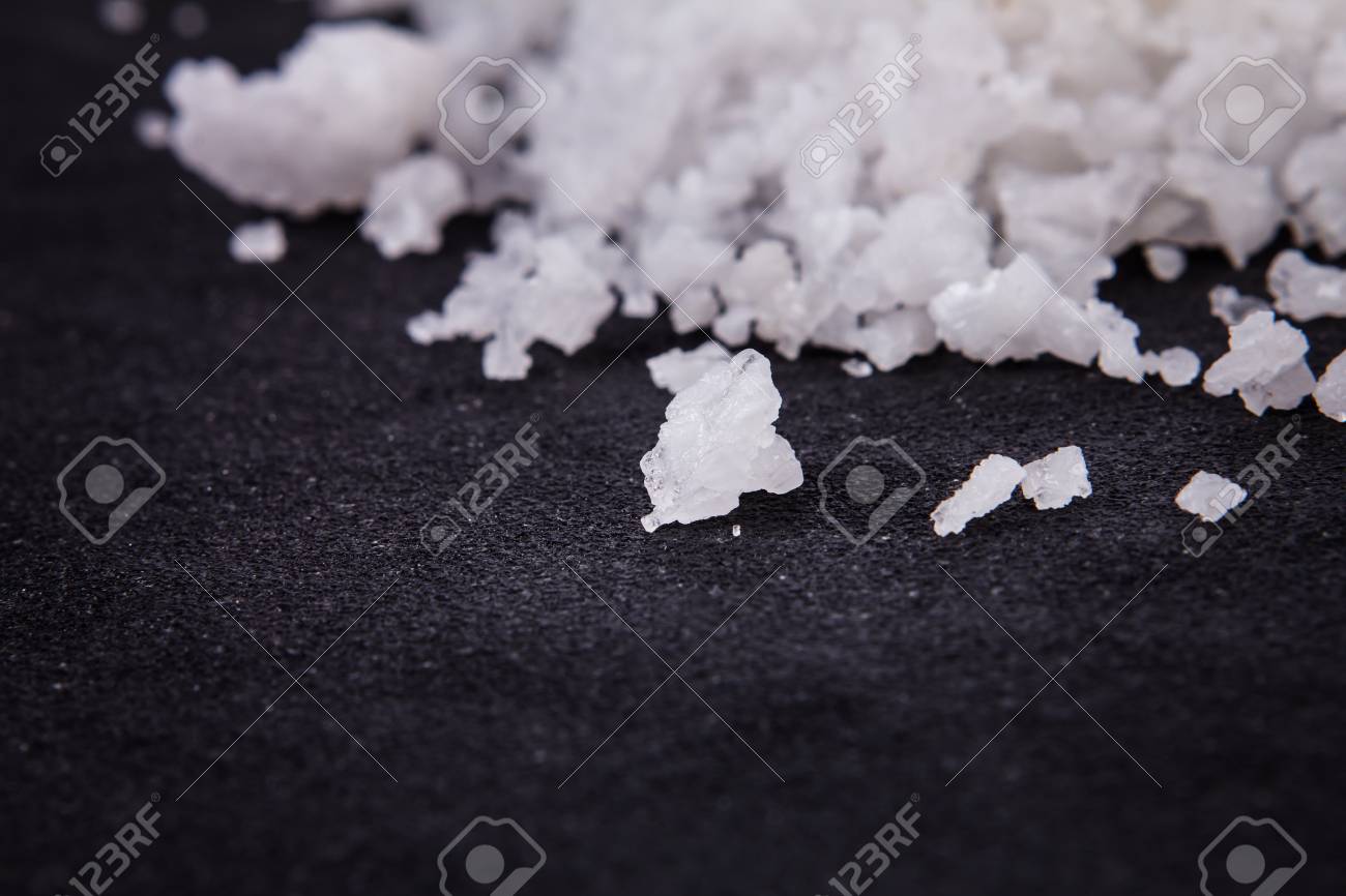 the salt crystals on black stone plate background stock photo