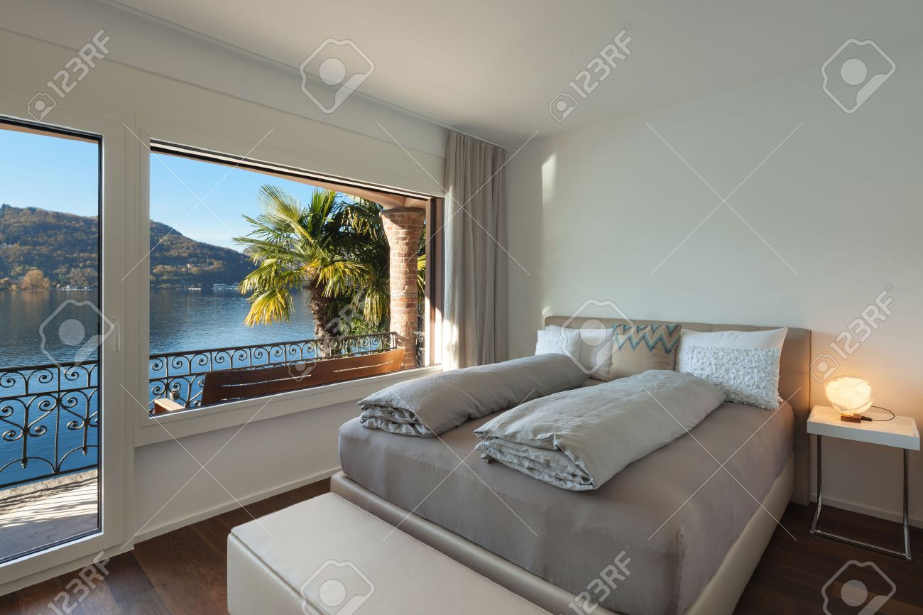 schönes schlafzimmer mit großem fenster, blick auf den see