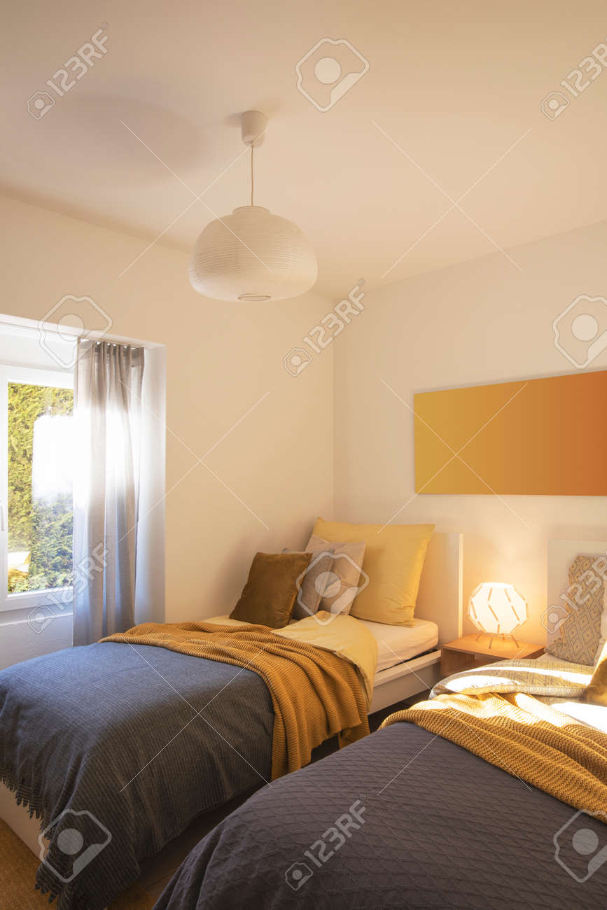 Modern bedroom with two singles beds with clean bed sheets and large pillow above. White wall. Nobody inside. - 163075635 Modern bedroom with two singles beds with clean bed sheets and large pillow above. White wall. Nobody inside. - 163075635