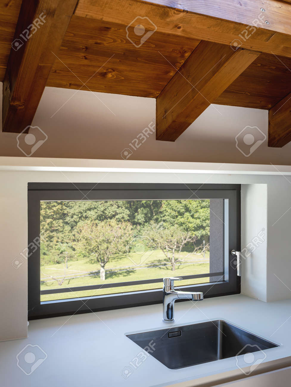 Modern white kitchen detail with steel sink and window overlooking nature. Natural light - 167299064 Modern white kitchen detail with steel sink and window overlooking nature. Natural light - 167299064
