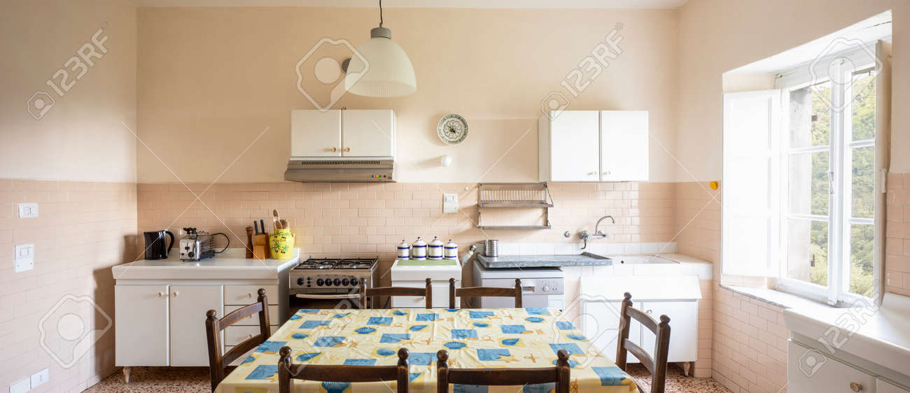 Interior of an old kitchen, almost antique, a table in the middle, the space is large and it is also bright. There is no style, they are pieces of furniture put together without aesthetic taste and the whole form romanticism - 171301157 Interior of an old kitchen, almost antique, a table in the middle, the space is large and it is also bright. There is no style, they are pieces of furniture put together without aesthetic taste and the whole form romanticism - 171301157