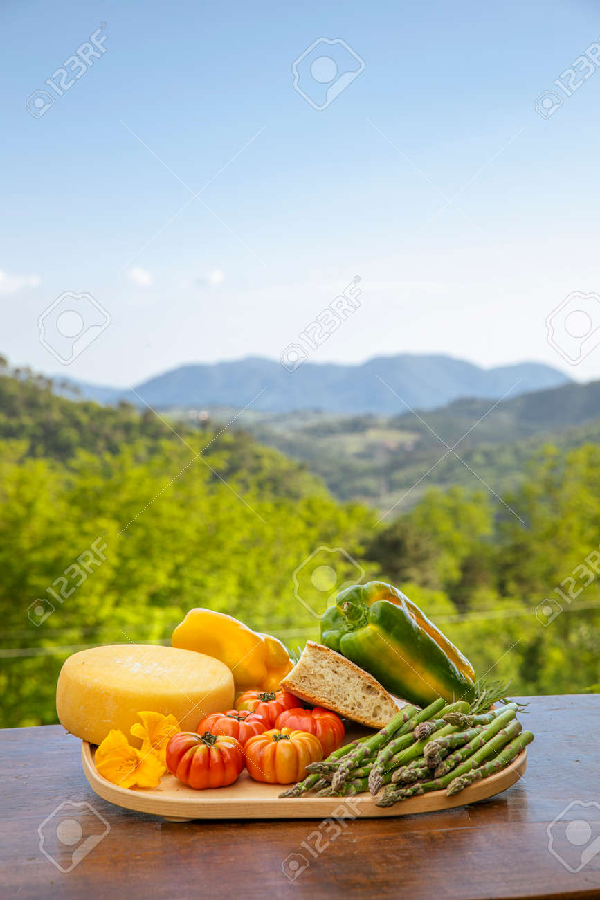 Plank of wood full of food from the land of Tuscany in Italy, peppers, salami, tomatoes. View on the Italian nature full of green plants. - 171317483 Plank of wood full of food from the land of Tuscany in Italy, peppers, salami, tomatoes. View on the Italian nature full of green plants. - 171317483