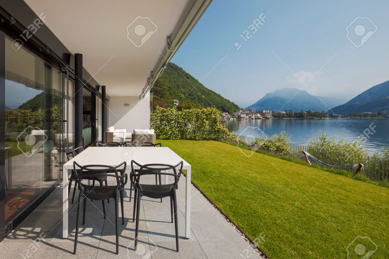 Modern house of two apartments with a beautiful garden directly on Lake Ceresio. Sunny day with blue sky. Minimalist and linear architecture. Panoramic view of the lake. Space for your text - 171413502 Modern house of two apartments with a beautiful garden directly on Lake Ceresio. Sunny day with blue sky. Minimalist and linear architecture. Panoramic view of the lake. Space for your text - 171413502