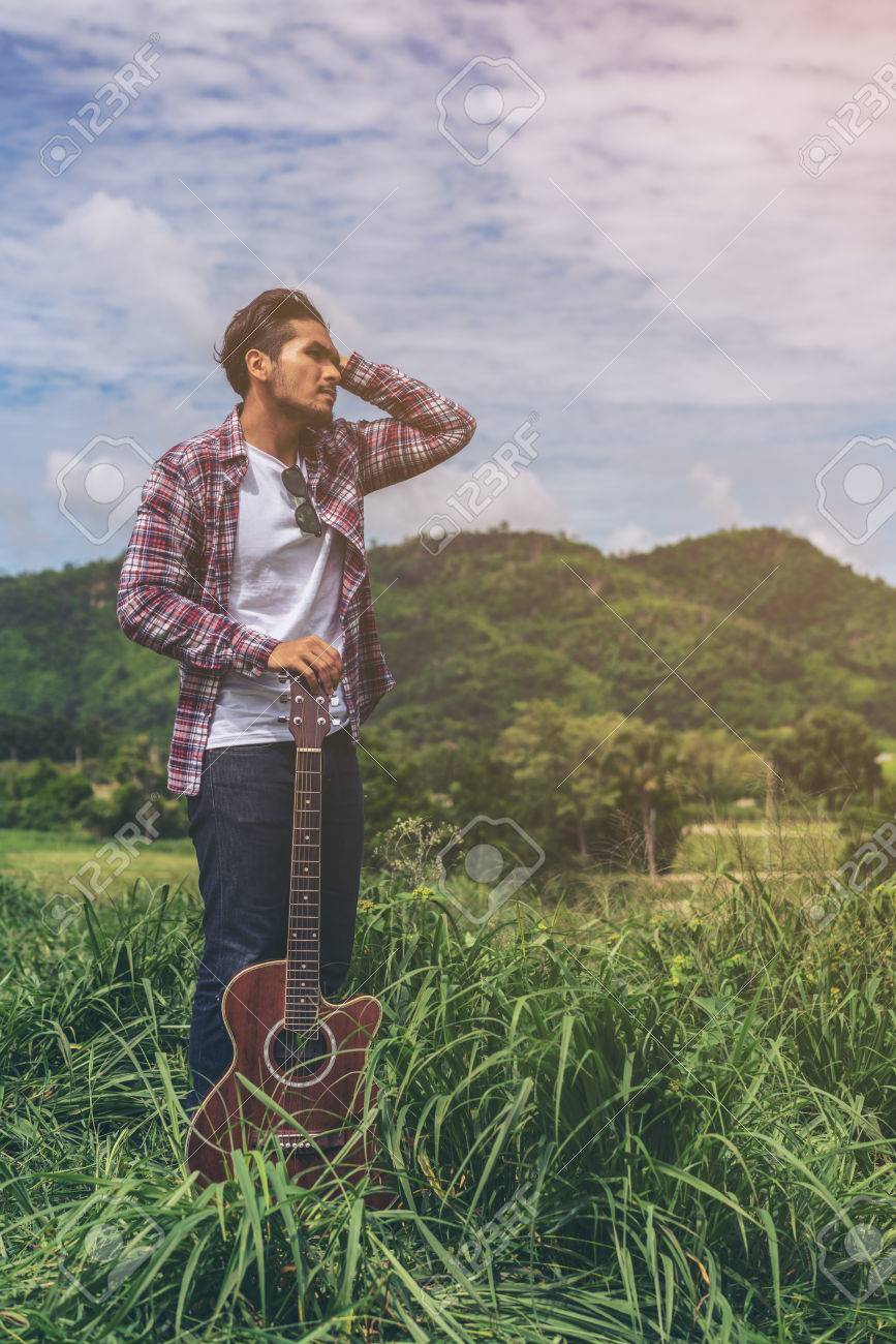 若い男が立って 後ろにマウンテン ビューとギターを保持します 音楽と自然の概念 の写真素材 画像素材 Image