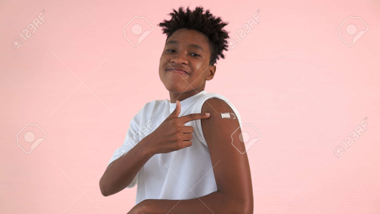 African American teenager showing COVID-19 vaccine bandage merrily in concept of coronavirus vaccination program to vaccinate citizen . - 171905694 African American teenager showing COVID-19 vaccine bandage merrily in concept of coronavirus vaccination program to vaccinate citizen . - 171905694