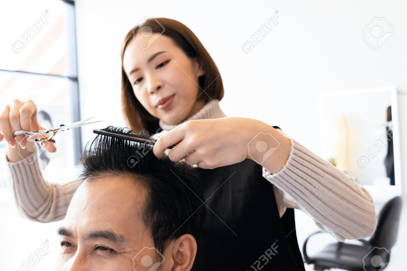 Cabeleireiro Fêmea Que Faz O Corte De Cabelo Masculino Com a