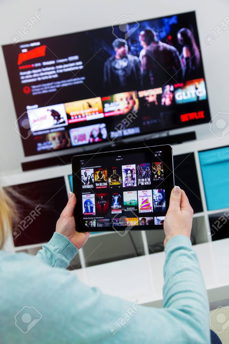 Benon, France - January 21, 2018: Woman Holding a touch pad and switching channels on France Netflix HomePage. with TV set on background. Netflix Inc. is an American multinational entertainment company founded on 1997 - 94171356 Benon, France - January 21, 2018: Woman Holding a touch pad and switching channels on France Netflix HomePage. with TV set on background. Netflix Inc. is an American multinational entertainment company founded on 1997 - 94171356
