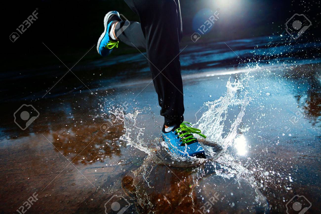 Single runner running in rain and making splash in puddle - 23684991 Single runner running in rain and making splash in puddle - 23684991