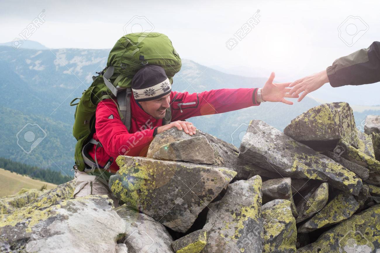 Helping hand - hiker man getting help on hike smiling happy overcoming obstacle. Hikers climbing on rock, mountain at sunset, one of them giving hand and helping to climb. Help, support, assistance in a dangerous situation. Concept teamwork. - 64476523 Helping hand - hiker man getting help on hike smiling happy overcoming obstacle. Hikers climbing on rock, mountain at sunset, one of them giving hand and helping to climb. Help, support, assistance in a dangerous situation. Concept teamwork. - 64476523