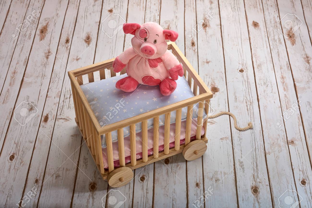 Piggy Toy Sitting On Pillows In A Toy Cart On A Wooden Floor