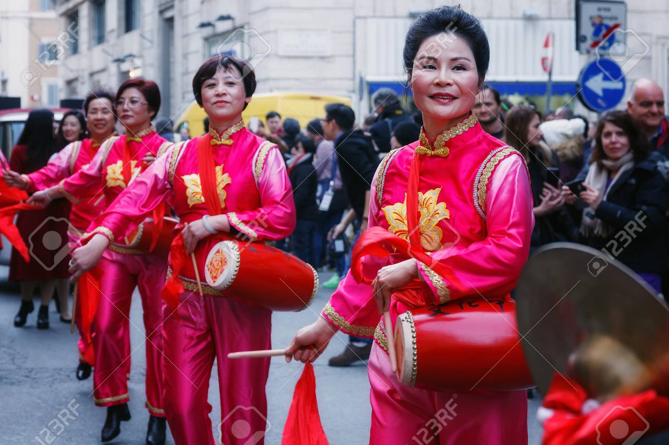 Eenheid kort Schildknaap Rome, Italië - 28 Januari 2017: Chinese Vrouwen In Traditionele Kleding, Spelen En Dansen Door De Straten Van De Hoofdstad, Tijdens De Processie Ter Viering Van Het Chinese Nieuwjaar In Het Jaar Eenheid kort Schildknaap Rome, Italië - 28 Januari 2017: Chinese Vrouwen In Traditionele Kleding, Spelen En Dansen Door De Straten Van De Hoofdstad, Tijdens De Processie Ter Viering Van Het Chinese Nieuwjaar In Het Jaar