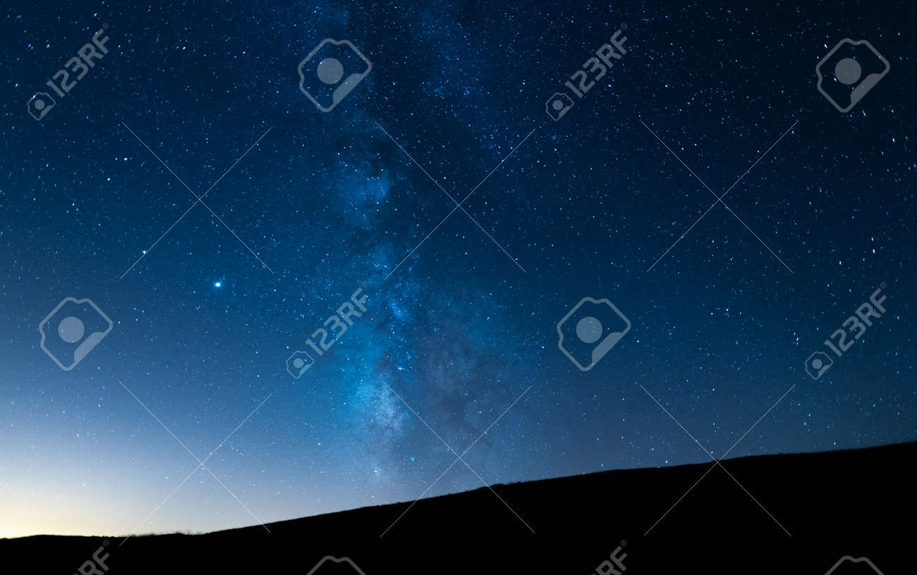 Milky way up a hill in a starry night sky. Blue sky with stars without light pollution. - 157794700 Milky way up a hill in a starry night sky. Blue sky with stars without light pollution. - 157794700