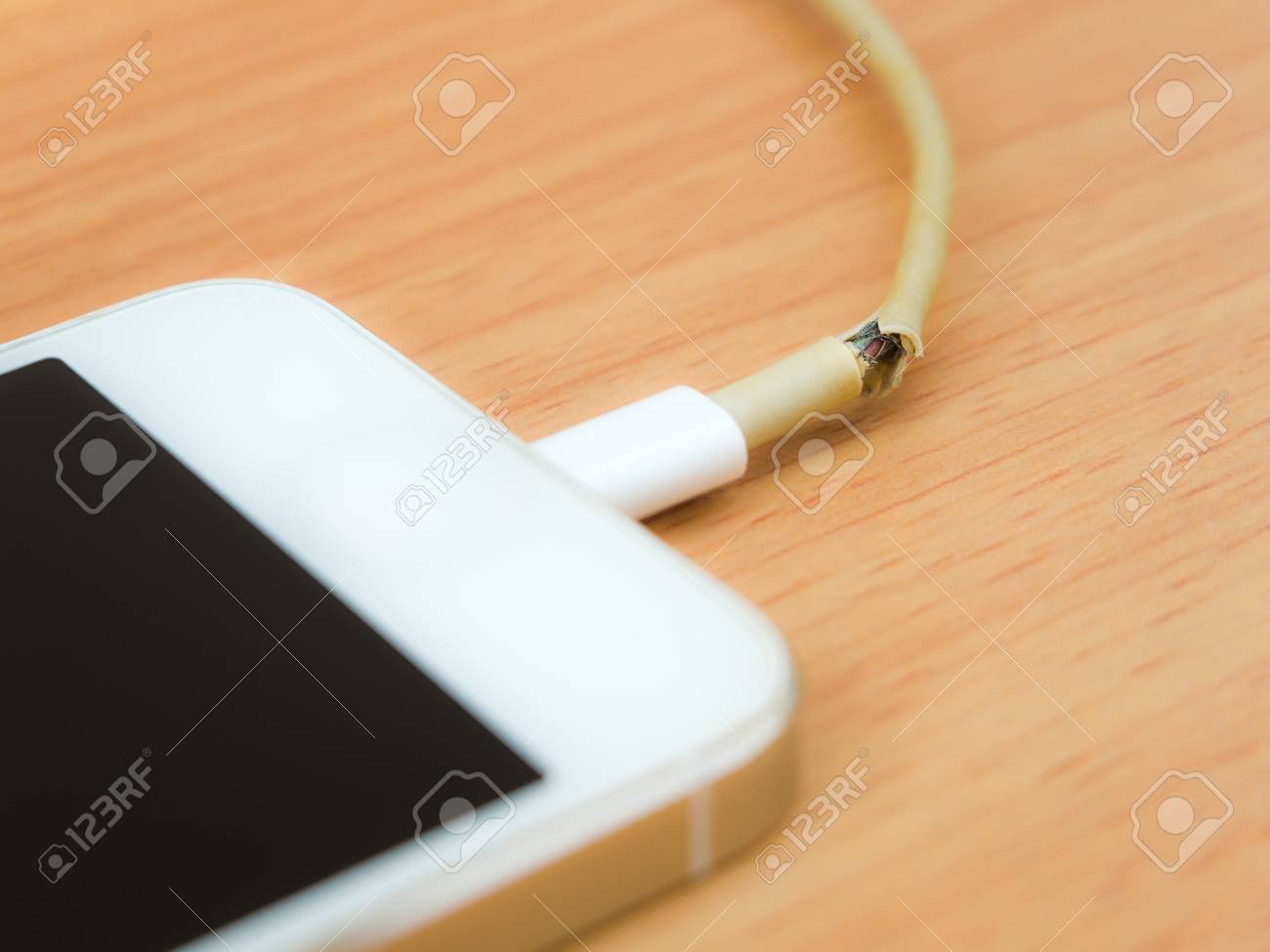木製のテーブルにスマート フォンで壊れた充電器のケーブルのクローズします の写真素材 画像素材 Image 5779