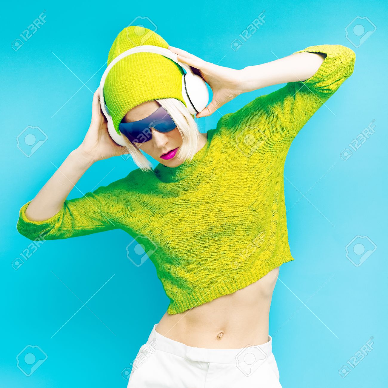 Glamorous Lada DJ in fashionable sportswear listening to Musik on blue background - 36050086 Glamorous Lada DJ in fashionable sportswear listening to Musik on blue background - 36050086