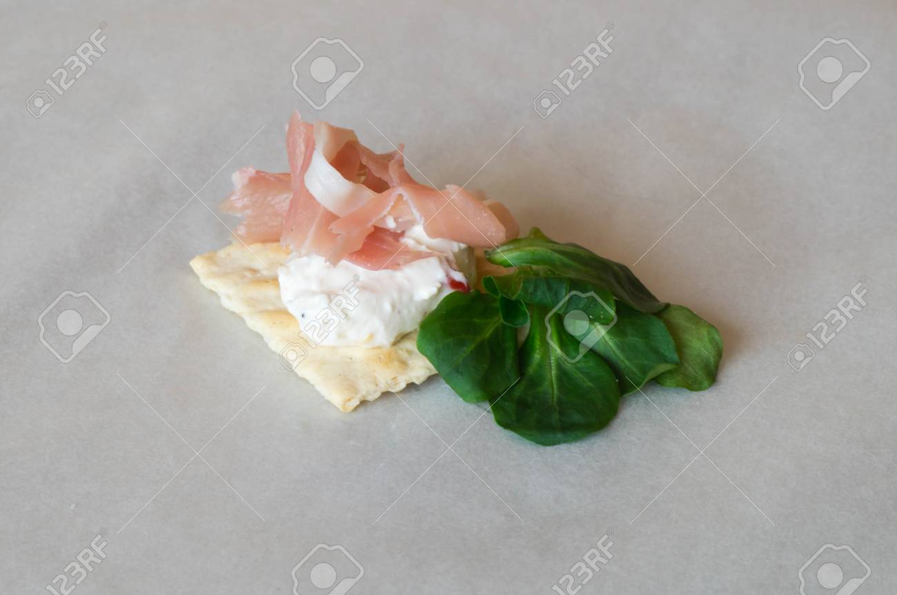 スモール サラダの葉で飾られたクリーム チーズのトッピングと生ハム クラッカーのワンピース の写真素材 画像素材 Image