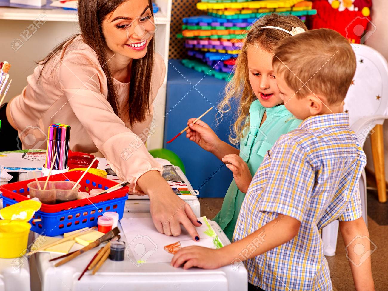 Children small group with teacher woman painting on paper at table in kindergarten . - 48472539 Children small group with teacher woman painting on paper at table in kindergarten . - 48472539
