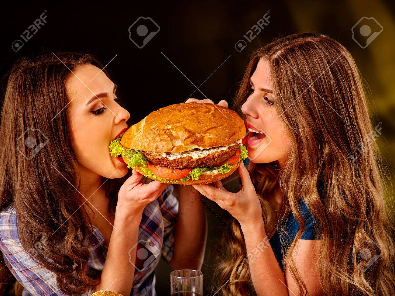 Girl holding and bite big hamburger from different sides. Fastfood concept. Cheeseburger on foreground. - 48930228 Girl holding and bite big hamburger from different sides. Fastfood concept. Cheeseburger on foreground. - 48930228