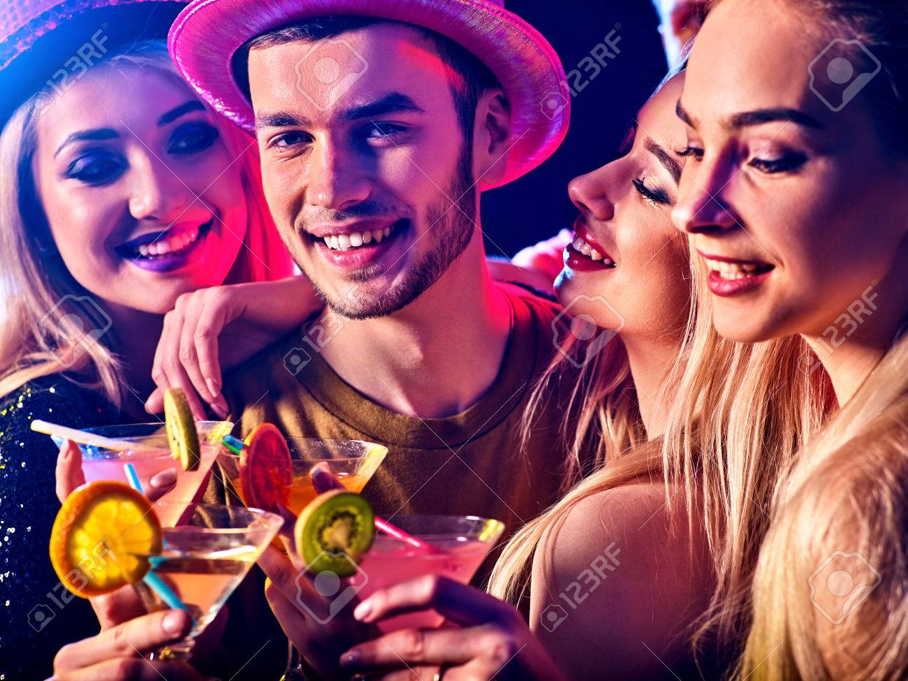 Dance party with group people dancing . Women and men have fun and drinking martini cocktail with fruit in night club. Happy man in hat on foreground . - 76760042 Dance party with group people dancing . Women and men have fun and drinking martini cocktail with fruit in night club. Happy man in hat on foreground . - 76760042