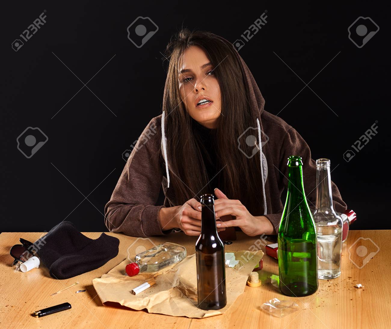 女性アルコール依存症社会問題 女性の飲酒は神経ストレスの原因です 彼女は気分が悪い緑のアルコールボトルの垂れ下がりでフードを被った テーブルの上の混乱 男と休憩した後のうつ病 の写真素材 画像素材 Image