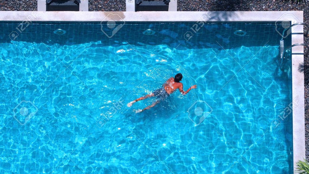 水泳プールのトップ画角で青い色の水と太陽の光を持っている人は 表面に反映されます の写真素材 画像素材 Image