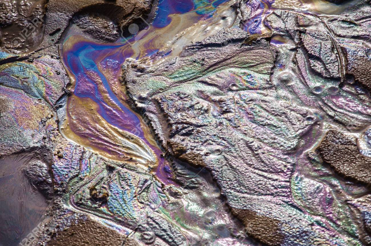 砂の上の虹の油膜。織り目加工の背景。水と地面の概念の汚染。 の写真 