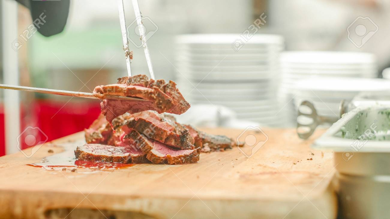 A chef slicing the meat and puting it on the plate - 56219569 A chef slicing the meat and puting it on the plate - 56219569