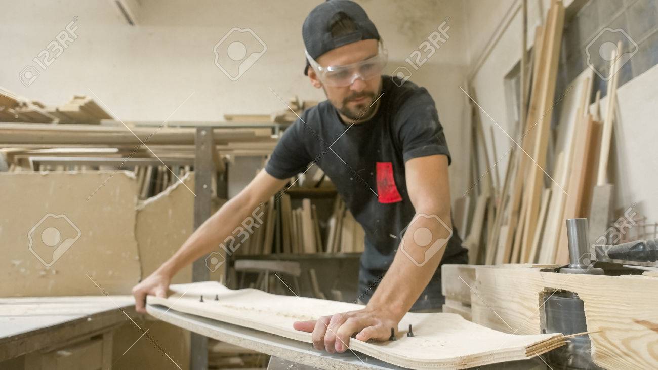 Young artisan man cutting longboard deck - 56219641 Young artisan man cutting longboard deck - 56219641