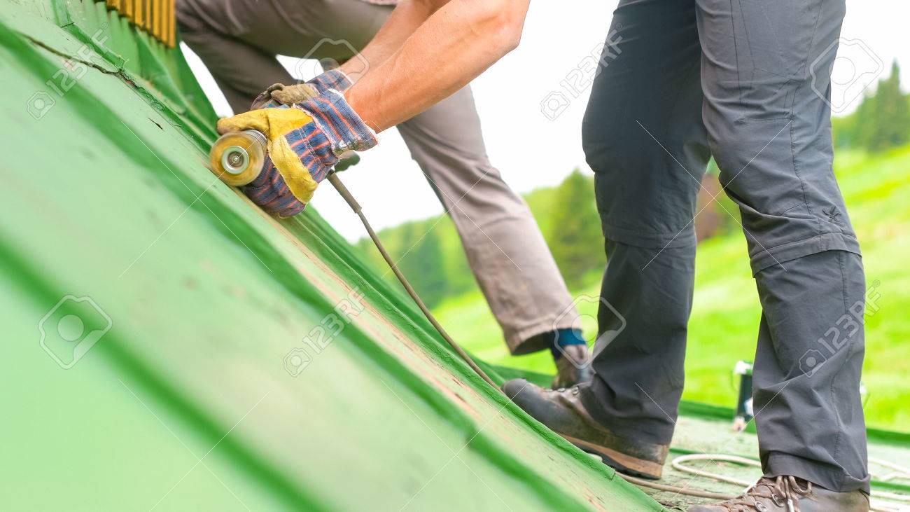 Construction worker using tools to scrape off green paint - 60155423 Construction worker using tools to scrape off green paint - 60155423