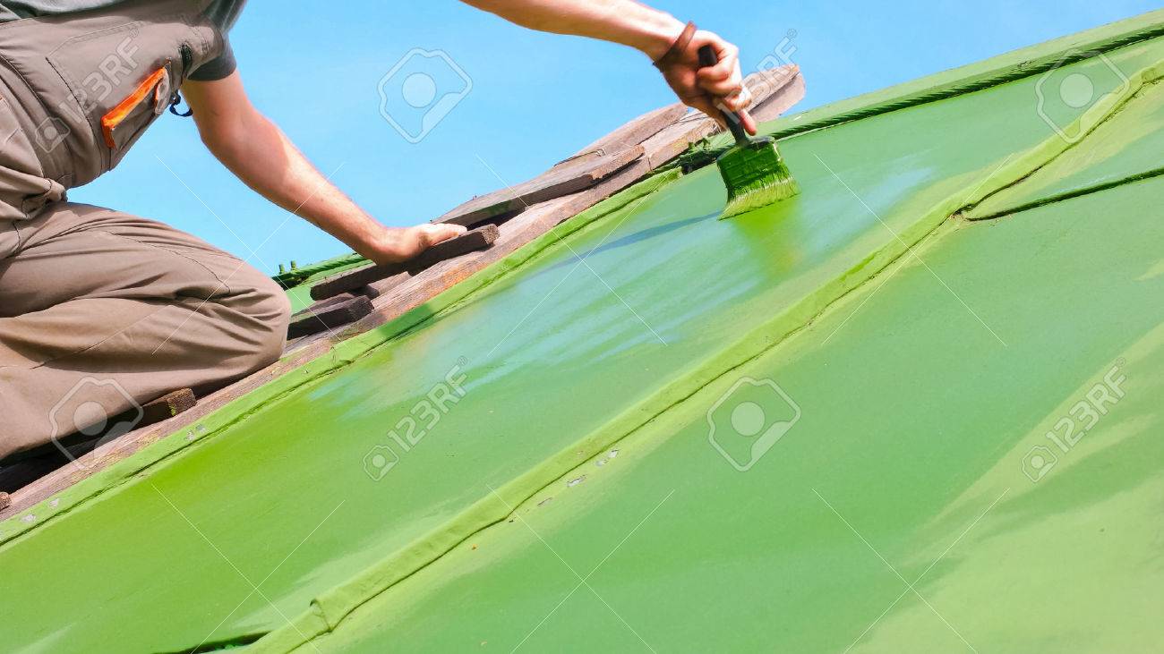 Adult caucasian man aplying second layer of paint to the roof - 60176898 Adult caucasian man aplying second layer of paint to the roof - 60176898