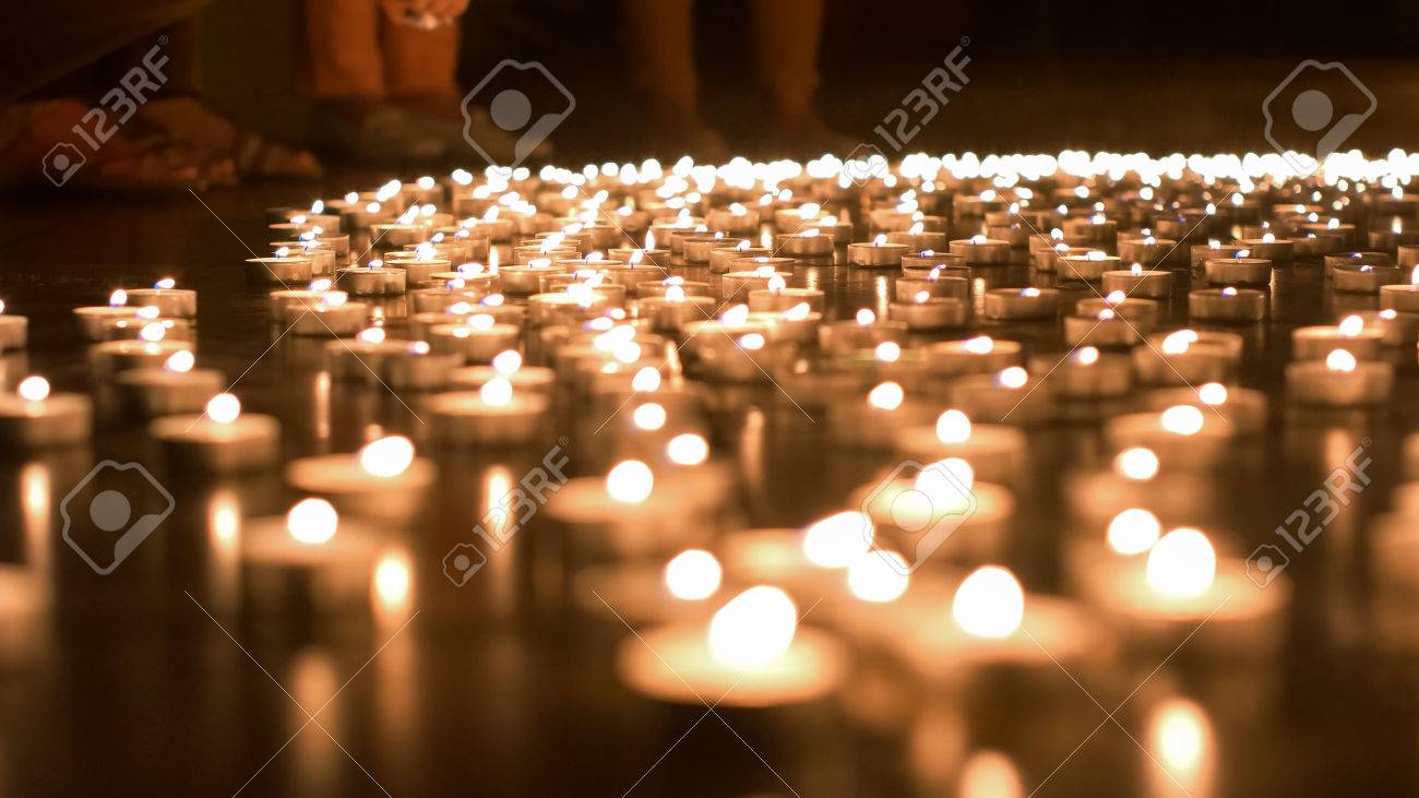 Religious adult caucasian man placing burning candle on the ground - 60533731 Religious adult caucasian man placing burning candle on the ground - 60533731