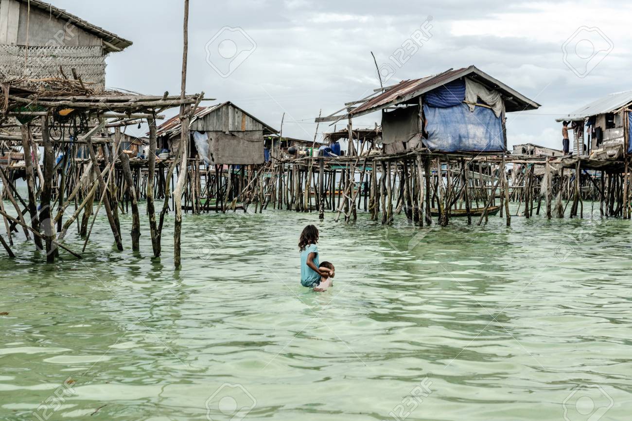 彼は海 サバ州センポルナ マレーシアに沈んで取得前に彼女の家に彼女の兄を運ぶバジャウ部族の女の子 の写真素材 画像素材 Image