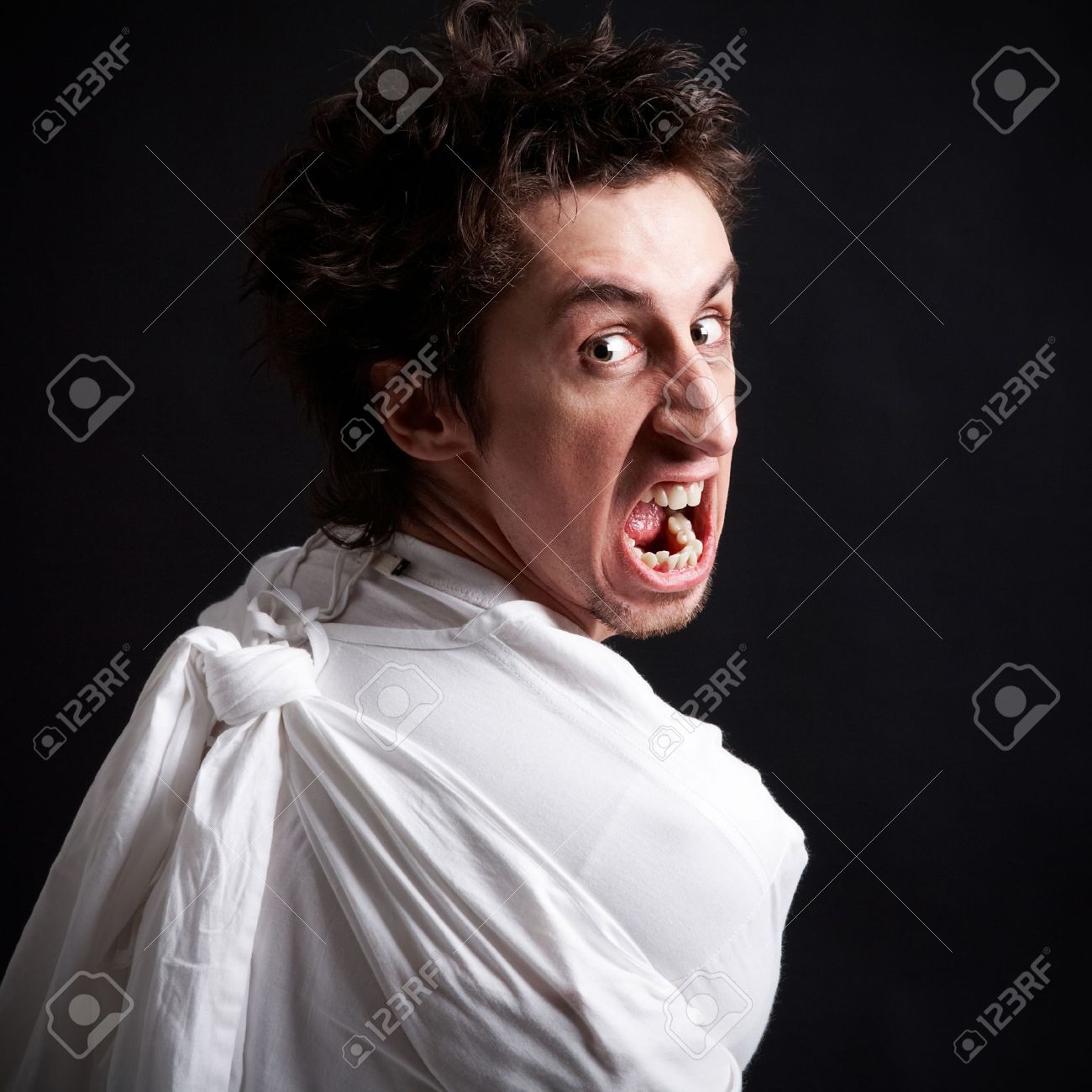 insane man in strait jacket screaming in isolation stock photo