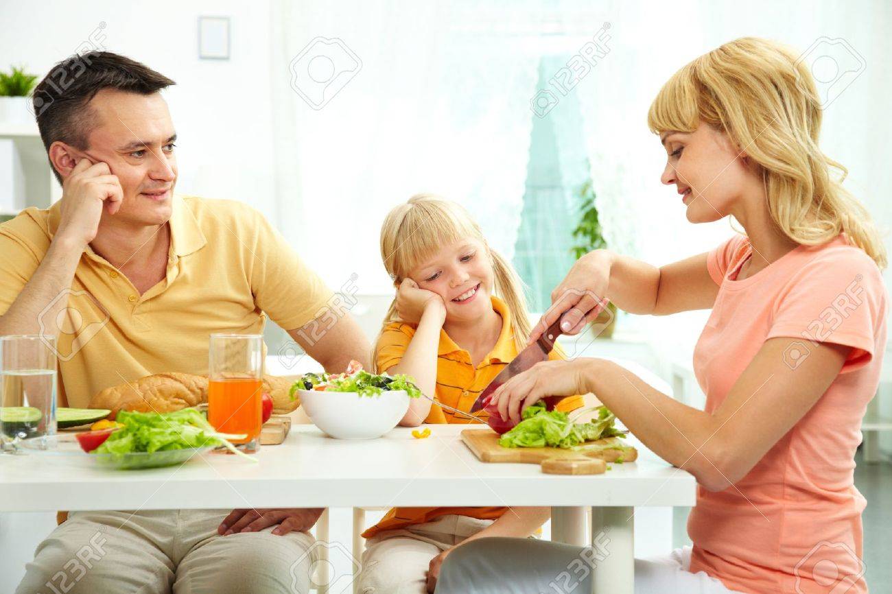 Family of three at table eating fresh vegetables - 12381188 Family of three at table eating fresh vegetables - 12381188