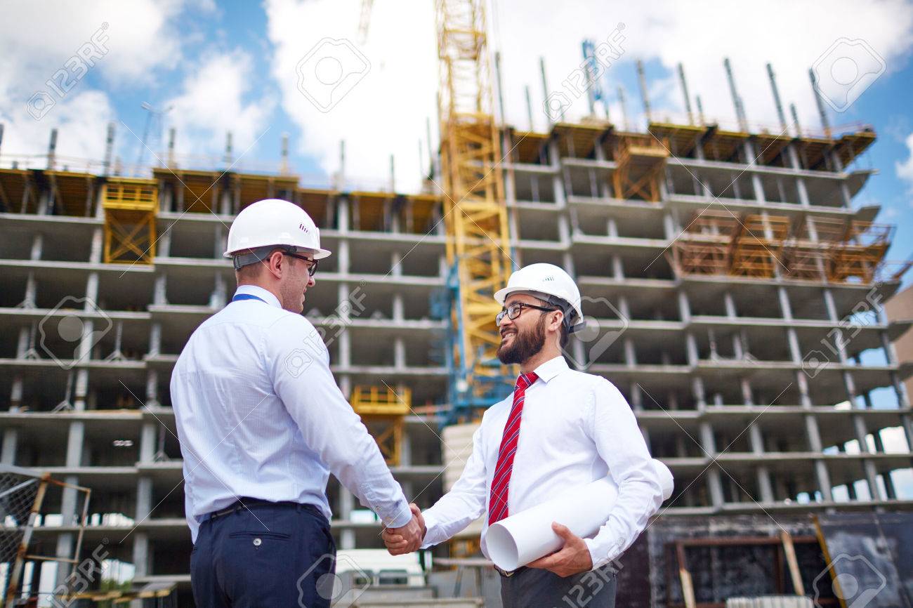 Two young partners handshaking on background of building structure - 52075953 Two young partners handshaking on background of building structure - 52075953