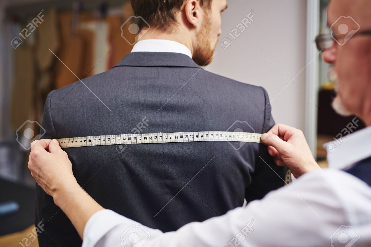Mature tailor measuring back of jacket worn by his client - 54234634 Mature tailor measuring back of jacket worn by his client - 54234634