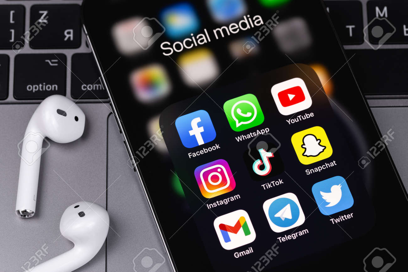 ソーシャルメディアアプリを表示フェイスブック、ワッツアップ、ユーチューブ、インスタグラム、ティクトク、スナップチャット、Gmail、電報、ツイッター  - エアポッドを搭載した画面スマートフォンiphone上のアプリ、マックブックキーボードの接写。モスクワ、ロシア ...
