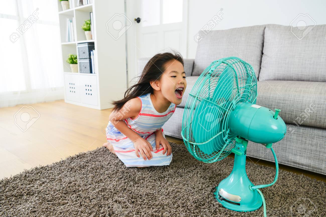 Reizendes Junges Weibliches Kind Das Zum Elektrischen Gerat Lacht Und Kuhles Wind Geniesst Sommerferien Zu Hause Im Wohnzimmer Zu Fangen Lizenzfreie Fotos Bilder Und Stock Fotografie Image 83257948