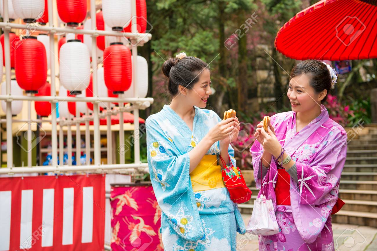 japanese women going to the local shrine tasting delicious dorayaki snacks ...