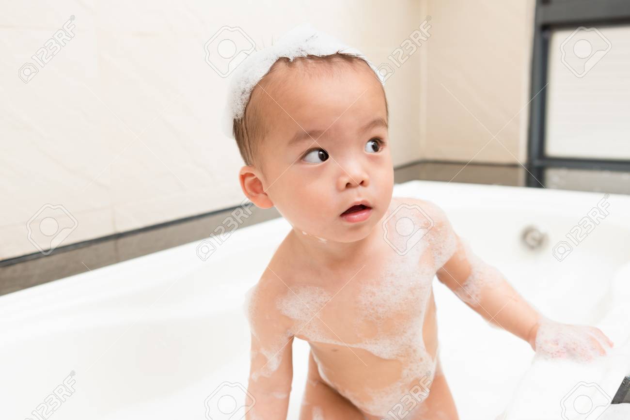 ハンサム愉快な男の子の子供たちが浴室の浴槽に立って泡バブル洗浄体を再生し 自宅で母親を探しています の写真素材 画像素材 Image