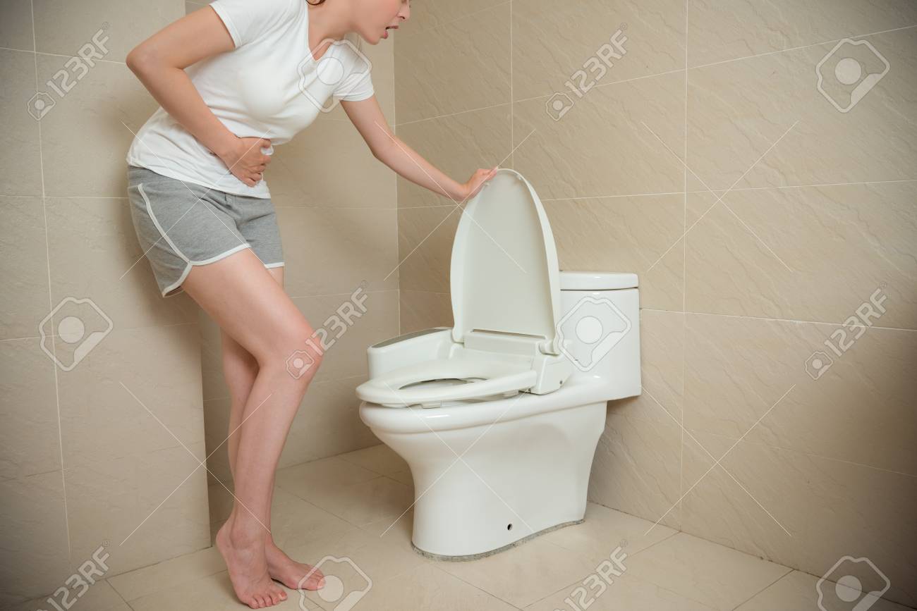 胃の痛みを感じ 下痢ができてトイレのふたを開いてトイレに行く苦痛の位置に触れる手を使って美しいエレガントな女の子 の写真素材 画像素材 Image
