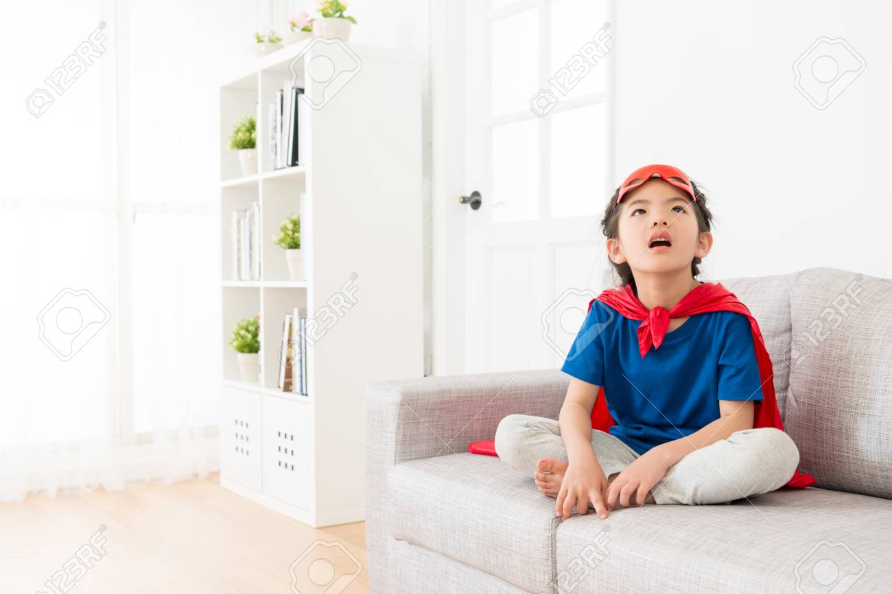 美しい若い小さな子供の子供の女の子はスーパーヒーローとしてプレーし 自宅で空想に生きているリビングルームのソファソファに座っています の写真素材 画像素材 Image